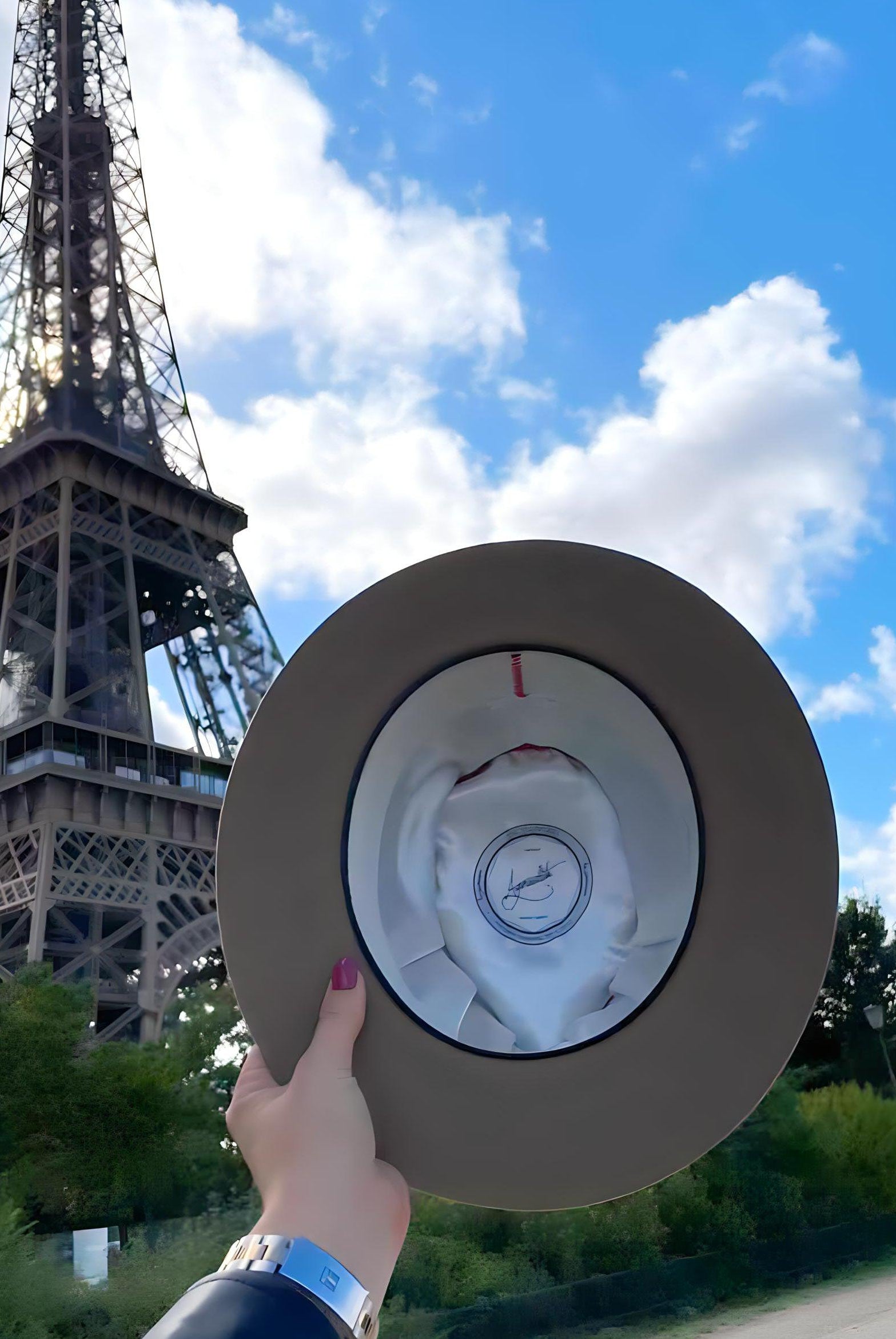woman showing off the inside of her Agnoulita fedora with the Eiffel Tower in Paris in the background