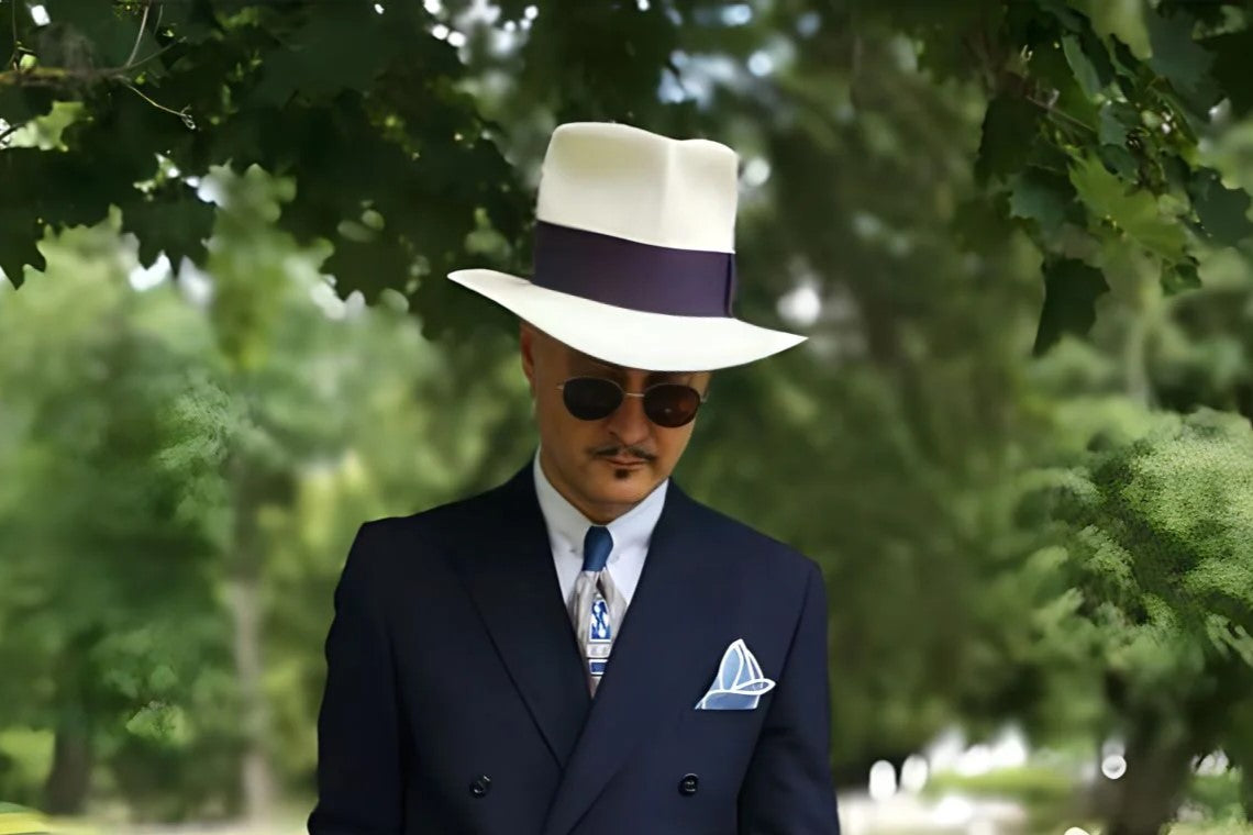 Park photo of a well dressed gentleman strolling in his white Agnoulita fedora