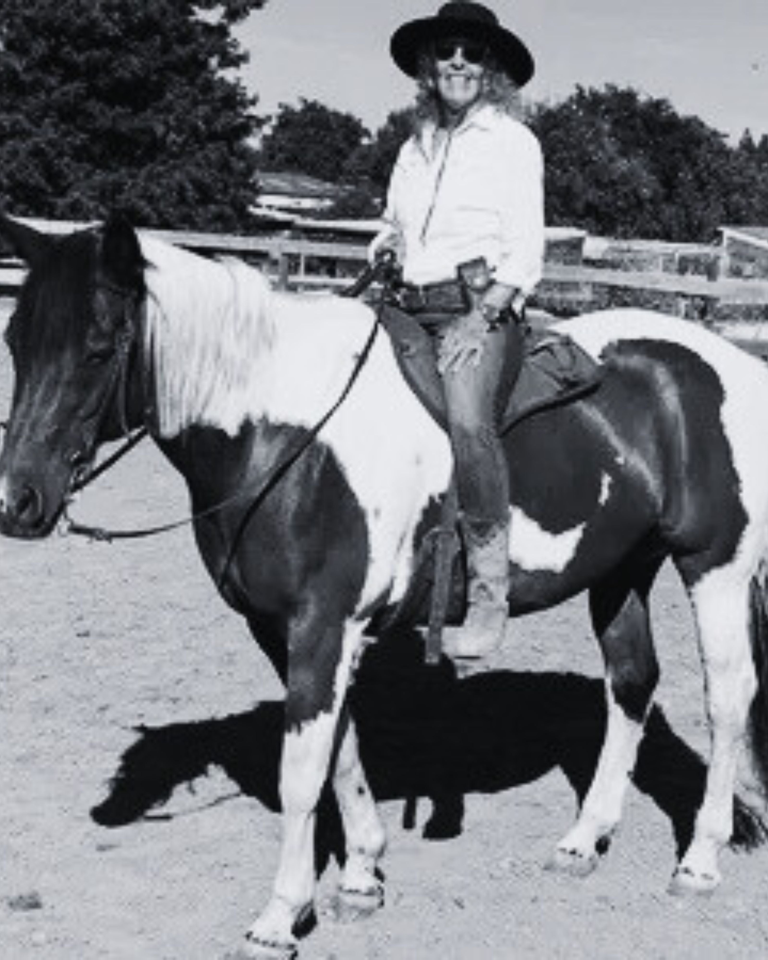 Person in a black Agnoulita hat riding a horse in an outdoor setting with trees in the background