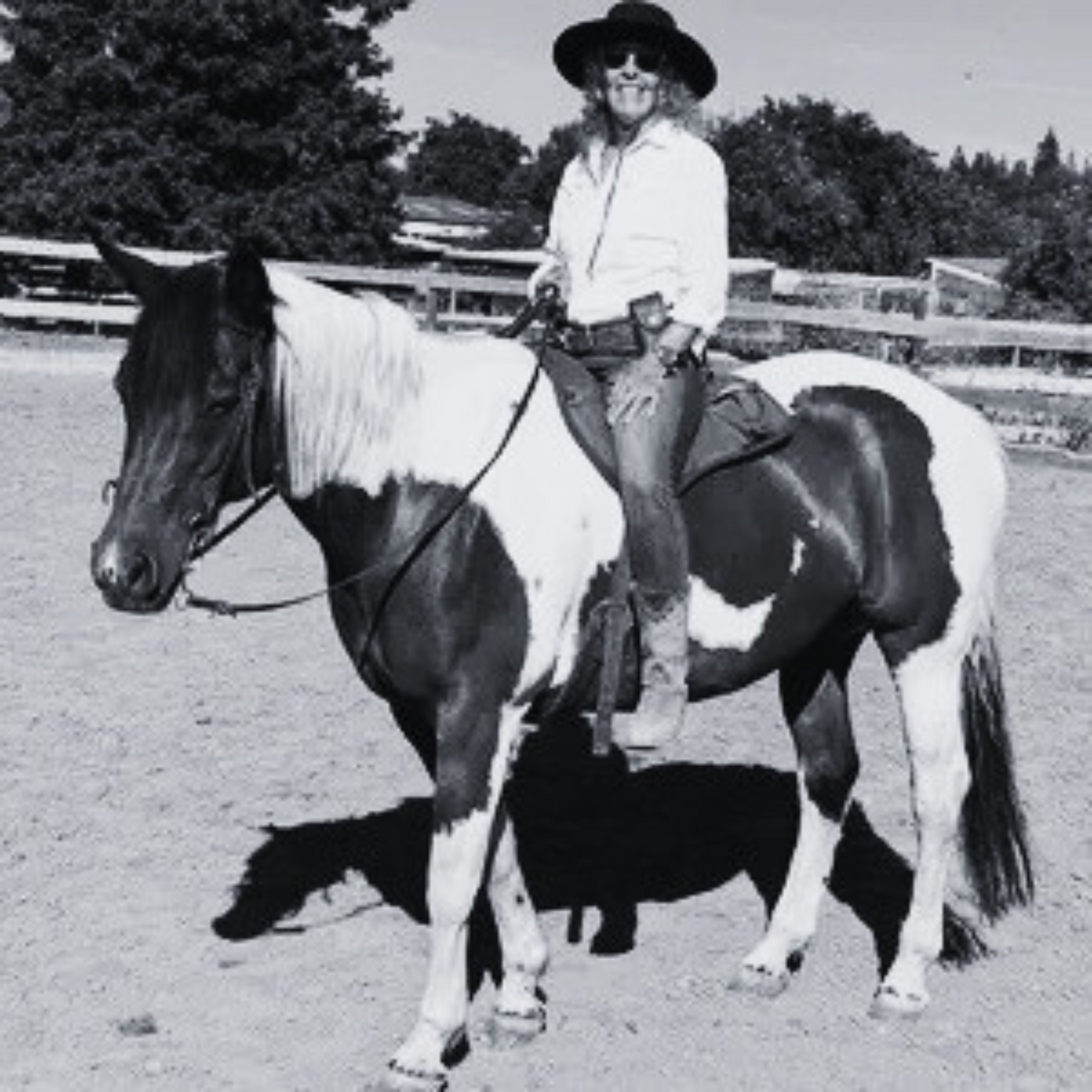 Person in a black Agnoulita hat riding a horse in an outdoor setting with trees in the background