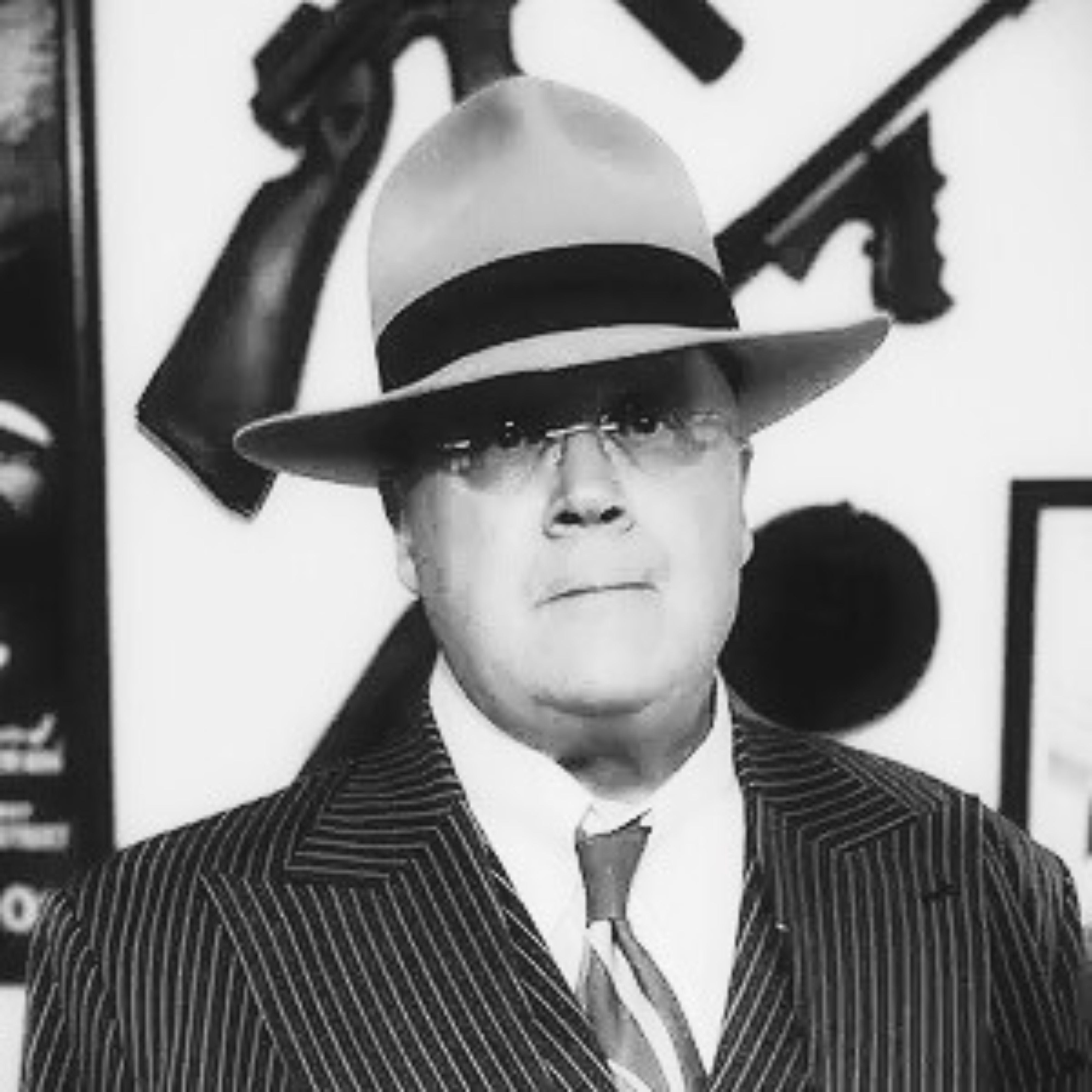 Black and white photo of a man wearing an Agnoulita hat and suit with a decorative background