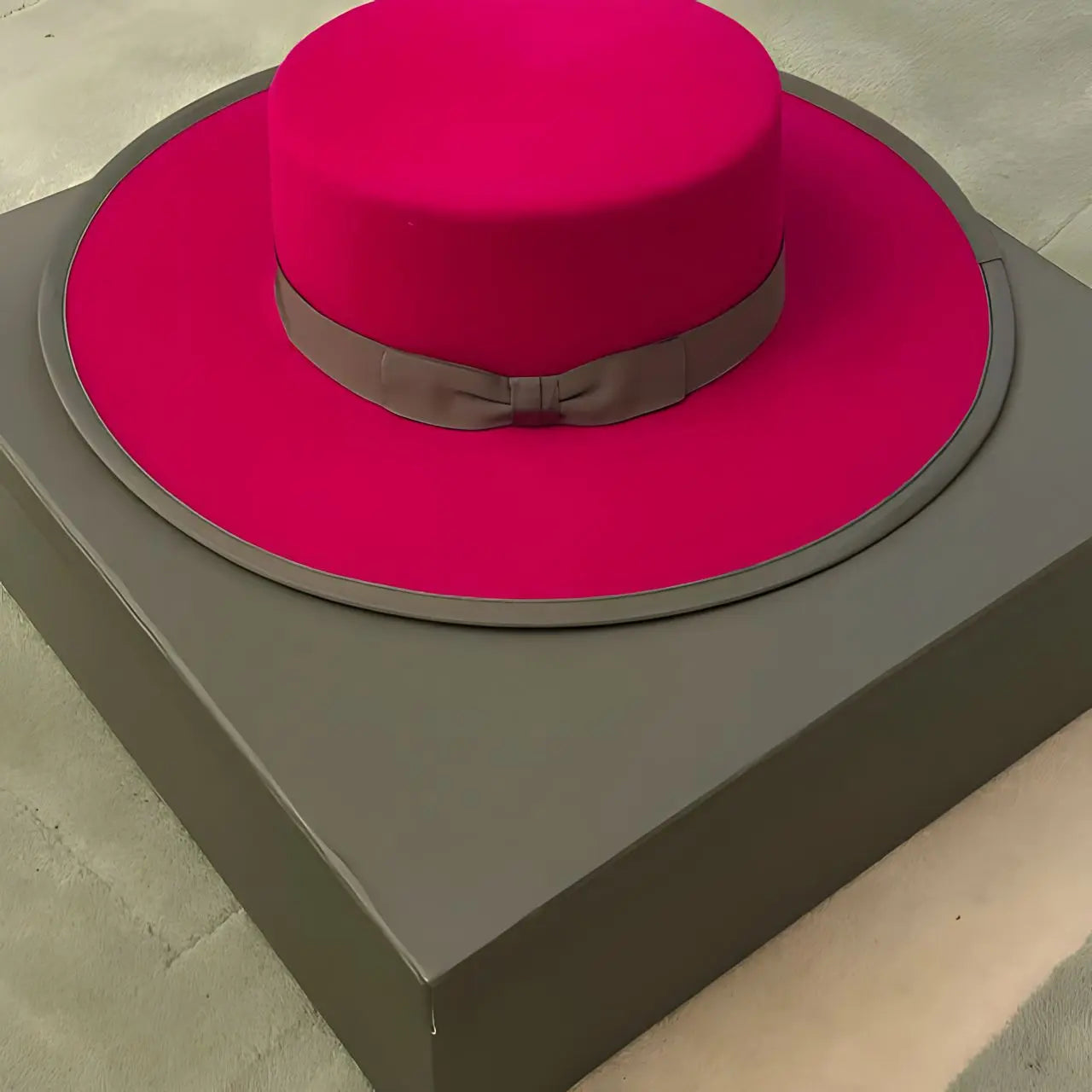 Fuchsia Agnoulita wide brim bolero hat displayed on top of a sturdy hat box