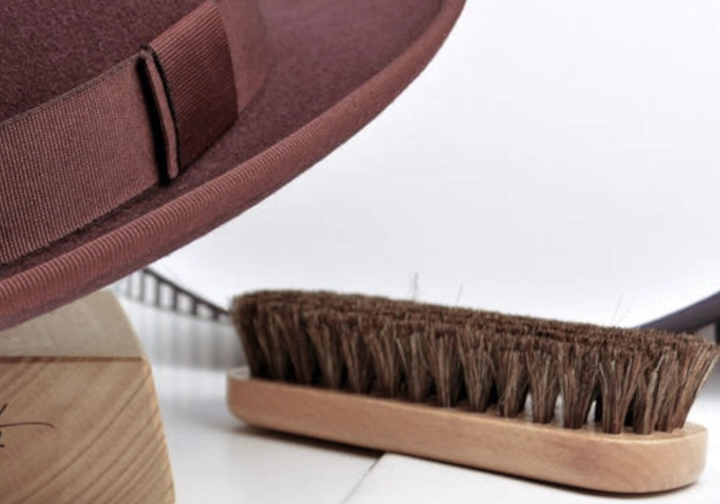 Studio photo featuring an Agnoulita Auxerre fedora, accompanied by a hat brush and a hat care instructions booklet.