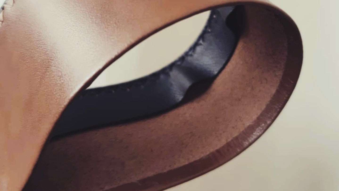 Close-up view of a rolled leather sweatband, highlighting the smooth, curved edge and fine stitching on a custom hat interior.