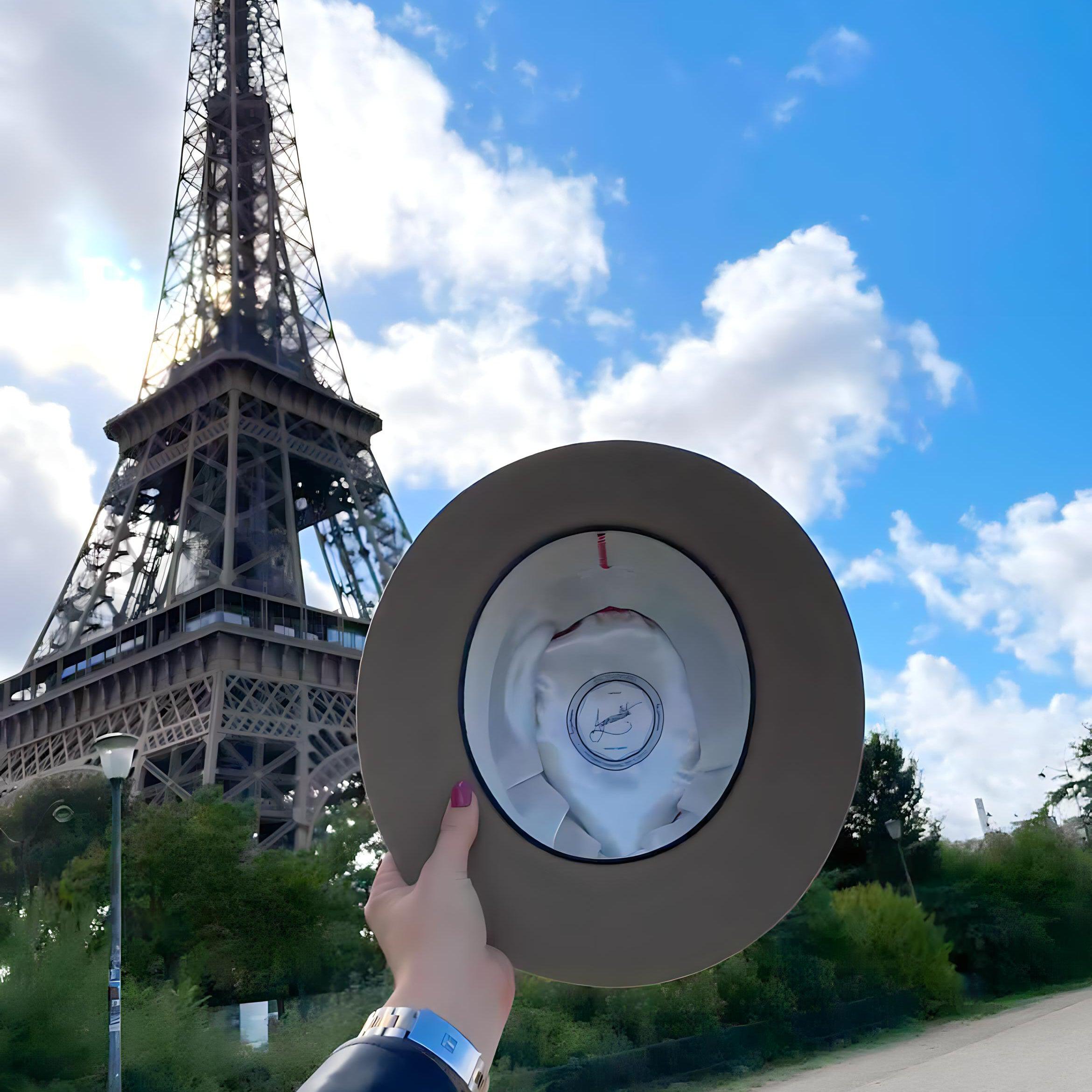 woman showing off the inside of her Agnoulita fedora with the Eiffel Tower in Paris in the background