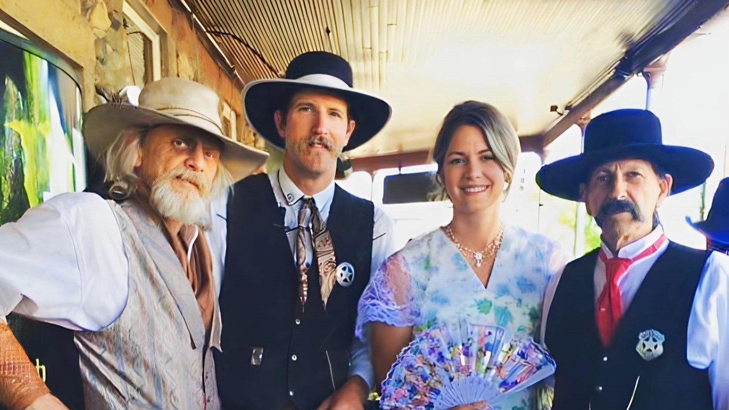 Group of four individuals in a vintage train setting, each wearing distinctive custom western hats, embodying a blend of traditional and contemporary western fashion.