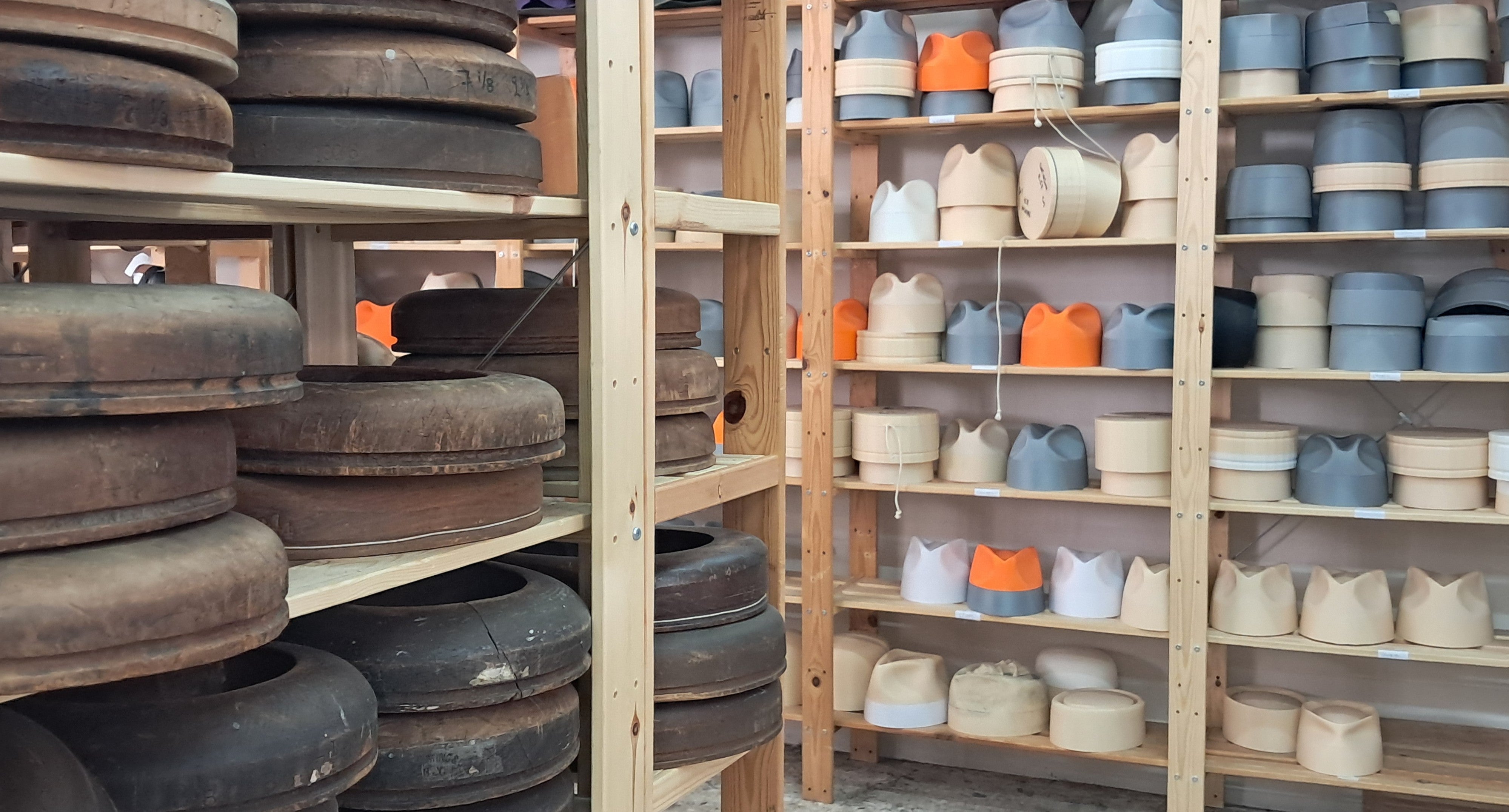 Shelves with hat brim flanges on the left and 3d printed hat blocks on the right in a hat workshop setting.