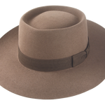 Artisanal wide-brim porkpie hat, named Oppenheimer, in premium beaver felt showcasing the raw edge brim and adorned with a vintage quality ribbon in pecan color against the coffee-hued backdrop of the hat body 1