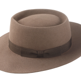 Artisanal wide-brim porkpie hat, named Oppenheimer, in premium beaver felt showcasing the raw edge brim and adorned with a vintage quality ribbon in pecan color against the coffee-hued backdrop of the hat body 2